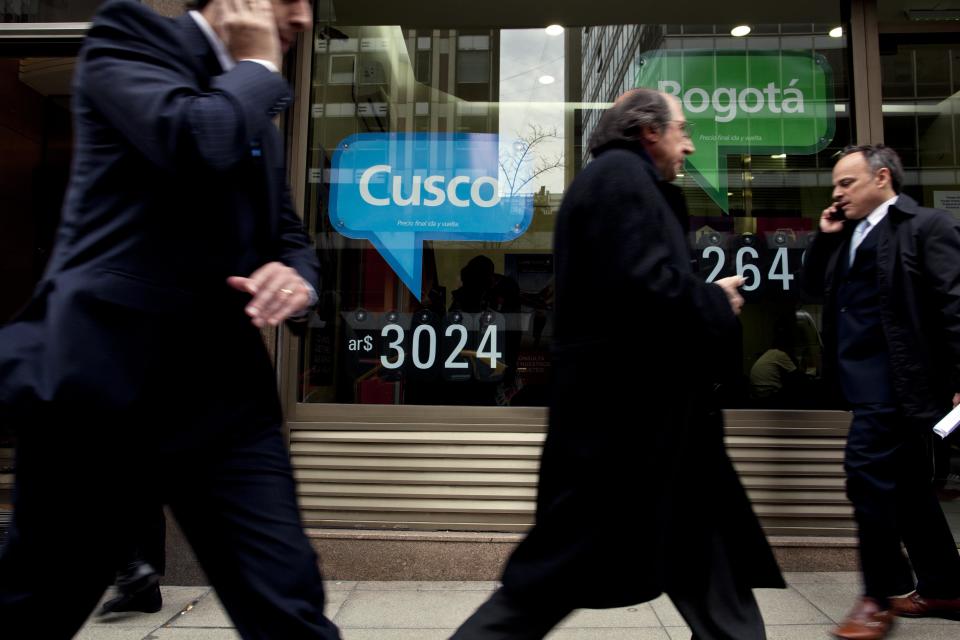 People pass by a travel agency offering trips to Bogota and Cusco, priced in Argentine pesos, in Buenos Aires, Argentina, Monday, Sept. 3, 2012. Argentines are increasingly feeling trapped inside their country as currency controls restrict them the foreign cash they need to travel. New rules taking effect this week aim to make using plastic outside the country less affordable by charging 15 percent in taxes on all foreign purchases that appear on credit or debit card bills, plus a 50-percent customs duty on any undeclared goods. (AP Photo/Natacha Pisarenko)