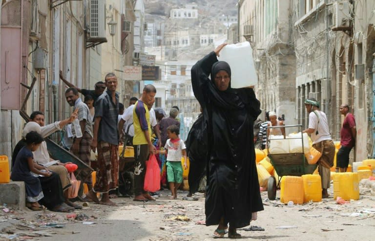 A Yemeni woman carries a plastic container filled with water in Aden on July 19, 2015