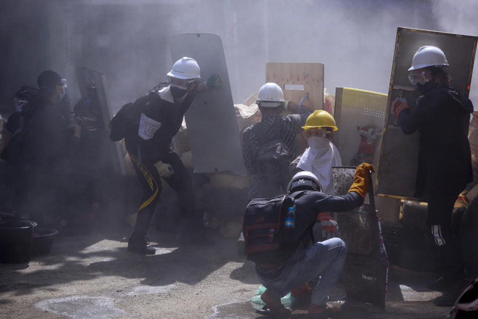 In this March 4, 2021, file photo, anti-coup protesters hide behind shields as police use tear gas during a demonstration in Yangon, Myanmar. Myanmar's security forces have killed scores of demonstrators protesting a coup. The outside world has responded so far with tough words, a smattering of sanctions and little else. (AP Photo, File)