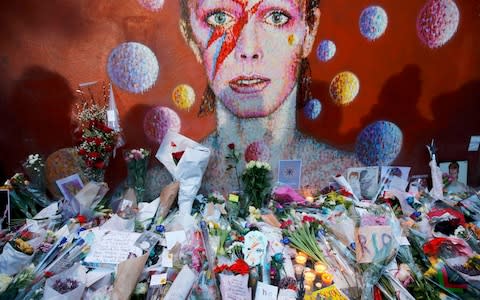 Flowers and tributes lie at a mural of David Bowie in Brixton - Credit: REUTERS/Stefan Wermuth