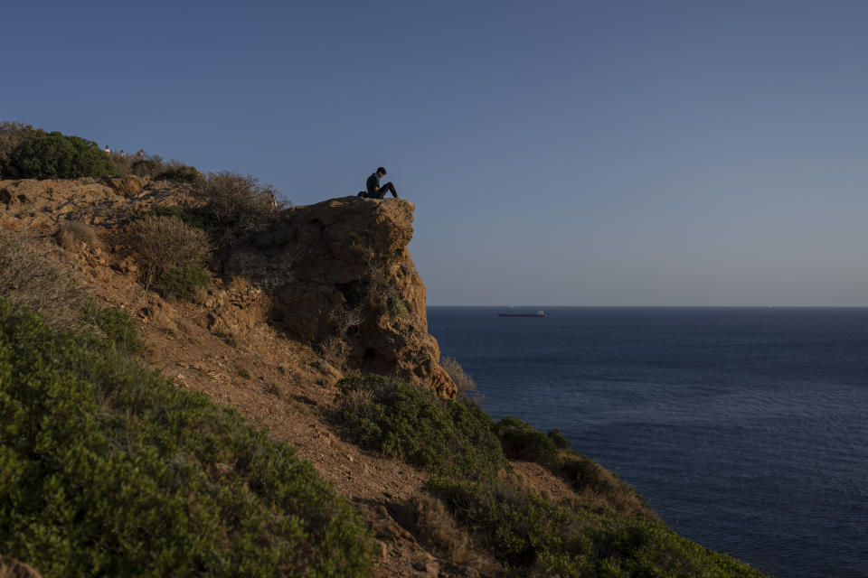 A Tourist sits inside the archaiological site of ancient temple of Poseidon at Cape Sounion, about 70 kilometers (45 miles) south of Athens, on Wednesday, Oct.12, 2022. As Europe tilts toward recession, with economies weighed down by high energy prices and other effects of the war in Ukraine, a strong rebound in tourism by southern European Union members has eased the continental slowdown. (AP Photo/Petros Giannakouris)