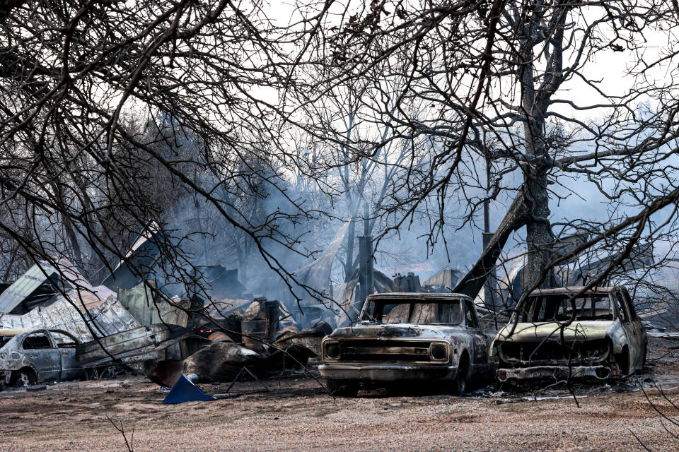 Burned cars and a home are pictured Friday after a wildfire in the Guthrie area.
