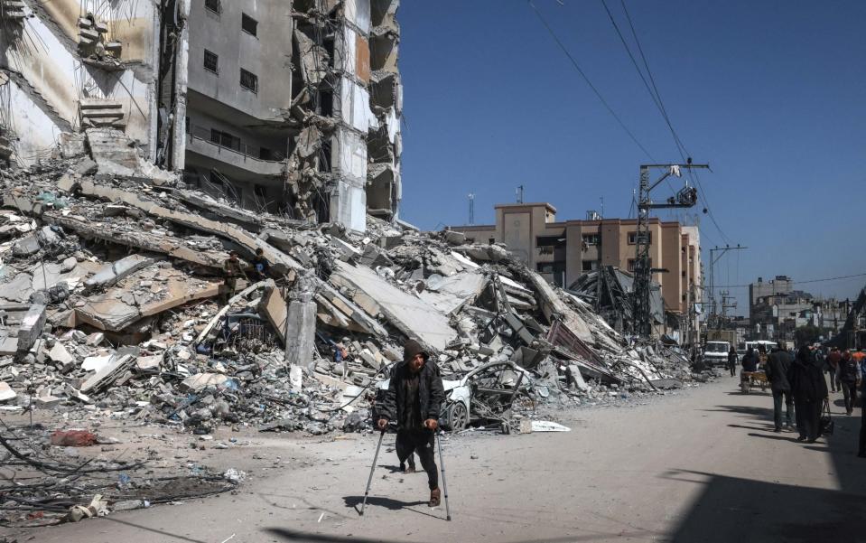 Palestinians walk past the rubble of a destroyed building due to Israeli bombardment