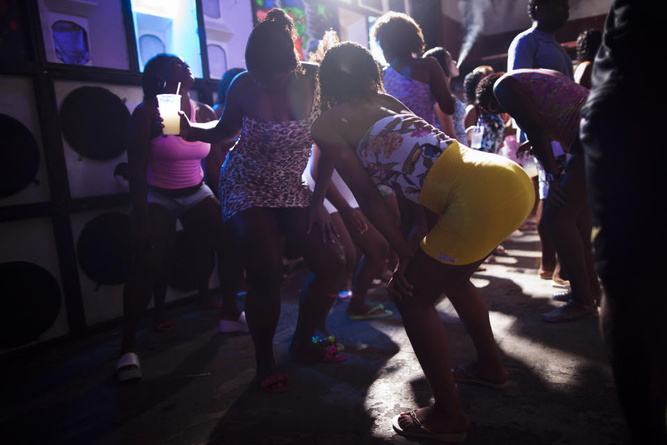 In this Feb. 3, 2012 photo, women dance during a funk "baile" in the Cantagalo slum in Rio de Janeiro, Brazil. Huge funk “bailes,” or parties, go on past dawn, packed with shirtless young men who can be heavily armed drug dealers, in slums far from police control. Subgenres can glorify the lifestyle of drug dealers, much like Mexico's narco-corridos, or simply serve as a titillating escape from the workaday grind. (AP Photo/Felipe Dana)