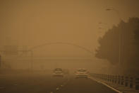 Cars drive in a cloud of red dust in Santa Cruz de Tenerife, Spain, Sunday, Feb. 23, 2020. Flights leaving Tenerife have been affected after storms of red sand from Africa's Saharan desert hit the Canary Islands. (AP Photo/Andres Gutierrez)