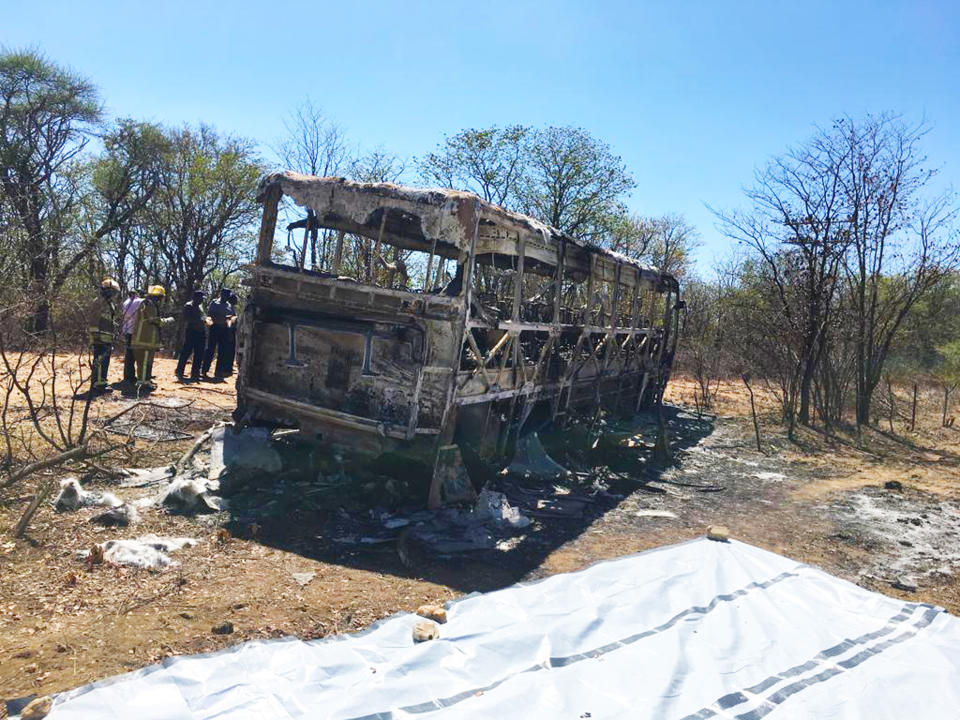 Emergency services stand near to a burnt out bus after a bus accident in Gwanda about 550 kilometres south of the capital Harare, Friday, Nov. 16, 2018. Police in Zimbabwe say more than 40 people have been killed in a bus accident on Thursday night. (AP Photo)