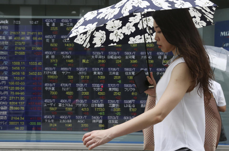 A woman walks by an electronic stock board of a securities firm in Tokyo, Tuesday, July 23, 2019. Asian stock markets rose on Tuesday on optimism over possible new U.S.-China talks despite rising Middle East tensions. (AP Photo/Koji Sasahara)