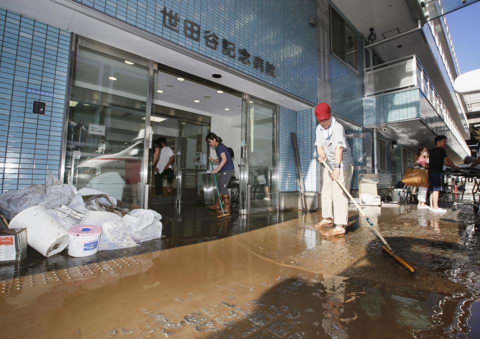 People clean a flooded hospital hit by Typhoon Hagibis, in Tokyo Sunday, Oct. 13, 2019. Rescue efforts for people stranded in flooded areas are in full force after a powerful typhoon dashed heavy rainfall and winds through a widespread area of Japan, including Tokyo.(Kyodo News via AP)