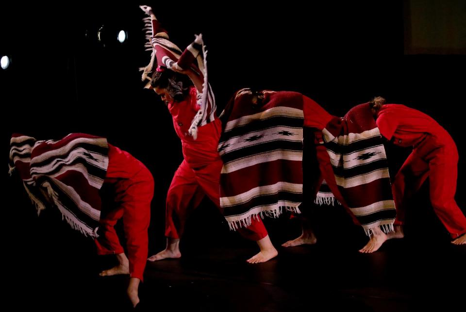 Primera Generacion Dance Collective dancing in a row together with Panchos hanging over their bodies.