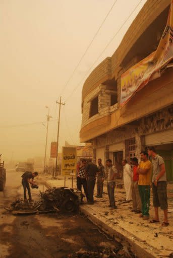 In the middle of a sand storm, Iraqis soliders inspect the debris following two car bombs in the western city of Ramadi, in the Anbar province