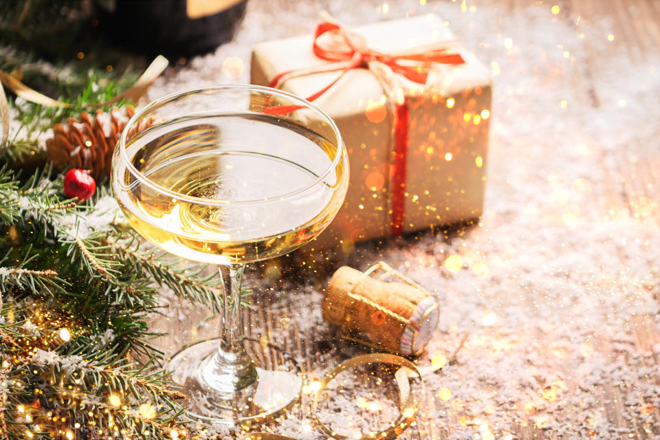 Champagner im eleganten Glas auf einem festlichen Weihnachtstisch mit Geschenk im Hintergrund 