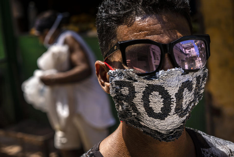 A youth wears a homemade face mask made of sequenced fabric amid the spread of the new coronavirus in Old Havana, Cuba, Friday, March 27, 2020. (AP Photo/Ramon Espinosa )