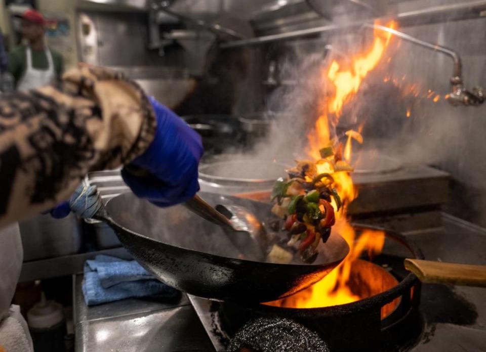 The flame of a gas stove flares up the side of a wok as chef Quan Sun cooks Chinese cuisine at Frank Fats in downtown Sacramento in May.