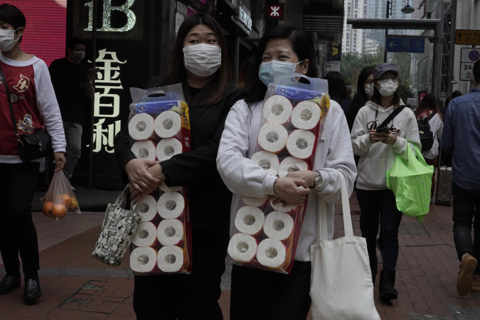 Two women carry supplies of toilet paper at a street in Hong Kong, Friday, Feb. 14, 2020. China on Friday reported another sharp rise in the number of people infected with a new virus, as the death toll neared 1,400. (AP Photo/Kin Cheung)