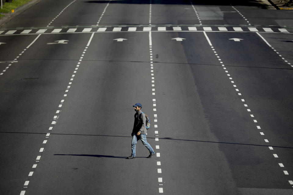 A man crosses an empty street in Buenos Aires, Argentina, Monday, March 23, 2020. The government has ordered a lock down until the end of the month to help contain the spread of the new coronavirus. (AP Photo/Natacha Pisarenko)