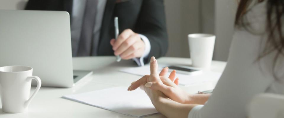 Close up of business people hands hold at an office desk, young man and woman are having a business talk. The woman feels stressed.