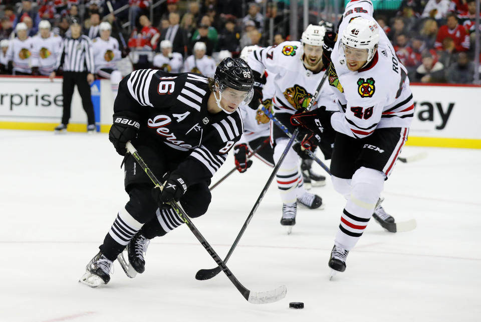 New Jersey Devils center Jack Hughes (86) is defended by Chicago Blackhawks defenseman Filip Roos (48) during the first period of an NHL hockey game Tuesday, Dec. 6, 2022, in Newark, N.J. (AP Photo/Noah K. Murray)