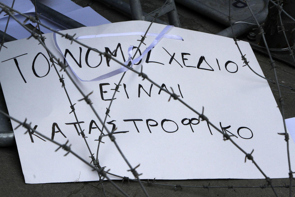 A banner that reads in Greek “The bill is disastrous” is seen through barbed wire during a strike to protest government plans to privatize the state-run organizations in Nicosia, Cyprus, Thursday, Feb. 27, 2014. Hundreds of protesters have gathered outside Cyprus' parliament to voice opposition against legislation that will pave the way for the privatization of state-owned companies. (AP Photo/Petros Karadjias)