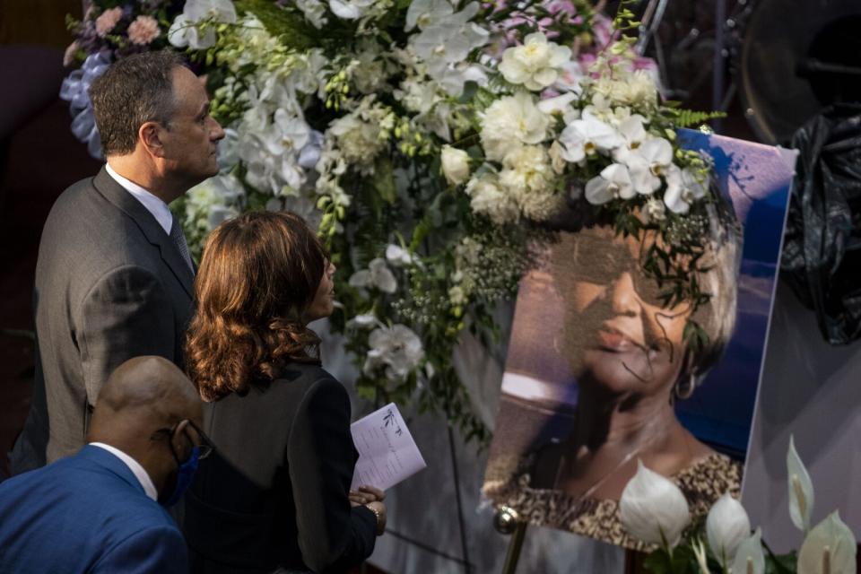 Kamala Harris and Second Gentleman Doug Emhoff look at a large photo of a woman.