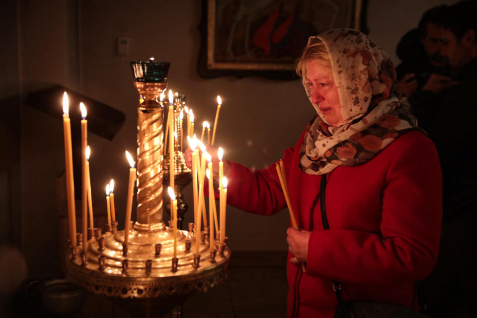 A woman places a burning candle on a stand during an Easter liturgy in the Ukrainian city of Bucha. Credit: Hennadii Minchenko/ Ukrinform/Future Publishing via Getty Images
