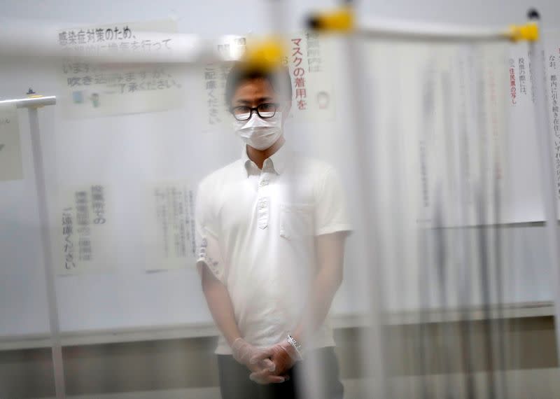 A member of Election Management Committee is seen between plastic curtains which are installed in order to prevent infections following the coronavirus disease (COVID-19) outbreak, at a voting station for the Tokyo Governor election in Tokyo