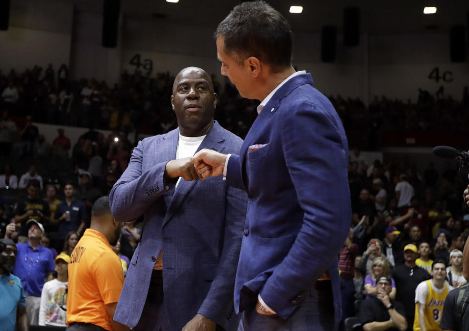 Los Angeles Lakers President of Basketball Operations Ervin Magic Johnson, left, bumps fists with General Manager Rob Pelinka before an NBA preseason basketball game against the Denver Nuggets, Sunday, Sept. 30, 2018, in San Diego. (AP Photo/Gregory Bull)