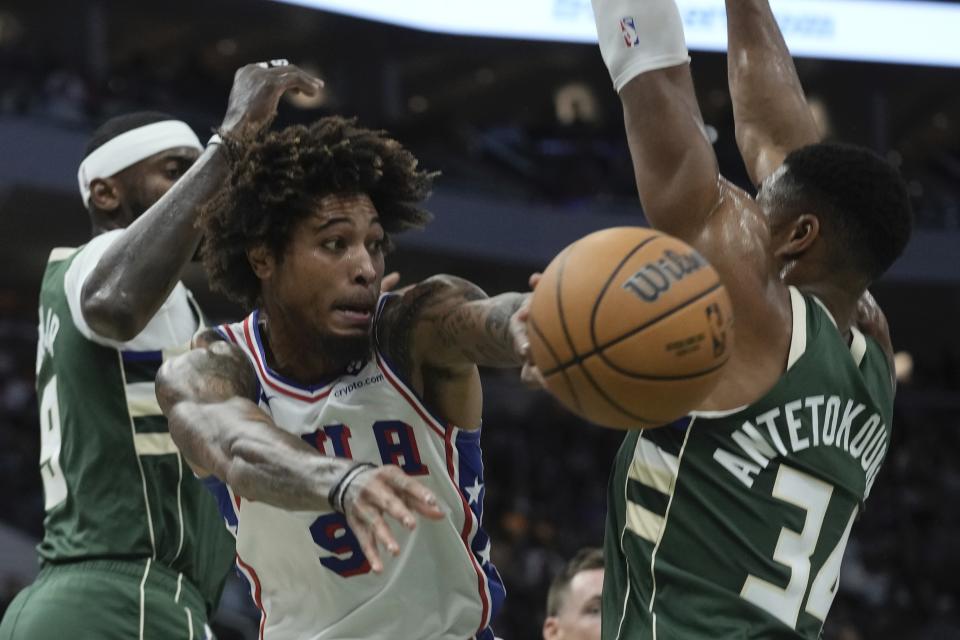 Philadelphia 76ers' Kelly Oubre Jr. asses between Milwaukee Bucks' Giannis Antetokounmpo and Bobby Portis during the first half of an NBA basketball game Thursday, Oct. 26, 2023, in Milwaukee. (AP Photo/Morry Gash)