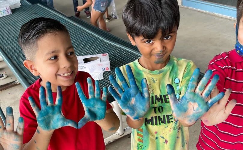 Students’ display stained hands after making tie-dye shirts at Crane School District’s “Camp Crane,” part of the AZ OnTrack initiative. (Crane School District / Twitter)