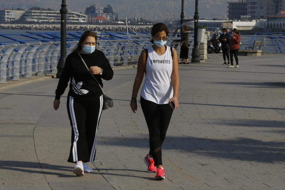 Two woman wearing face masks to help protect themselves from the coronavirus exercise on Beirut's Mediterranean seaside corniche, Lebanon, Monday, Jan. 4, 2021. Lebanon is gearing up for a new nationwide lockdown, as officials vowed Monday to take stricter measures against the coronavirus following the holiday season, which saw a large increase in infections and caused jitters in the country's already-battered health sector. (AP Photo/Bilal Hussein)