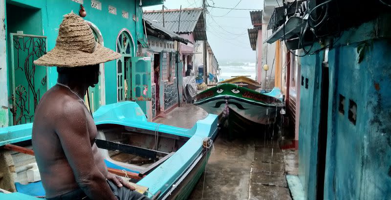 A fisherman sits on top a boat after pulling it back to land as Cyclone Burevi is expected to near the coast of Trincomalee