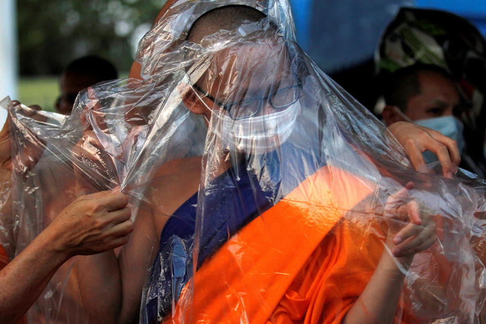 A monk covers with himself with a rain poncho in Pathum Thani