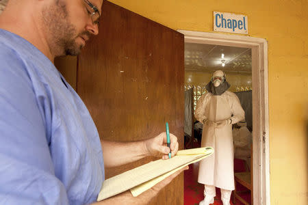 Dr. Kent Brantly (R) of Samaritan's Purse relief organization is shown in this undated handout photo provided by Samaritan's Purse, wearing personal protective equipment as he gives orders for medication to the Ebola patients through the doorway of the isolation unit at the case management center on the campus of ELWA Hospital in Monrovia, Liberia. REUTERS/Samaritan's Purse/Handout via Reuters