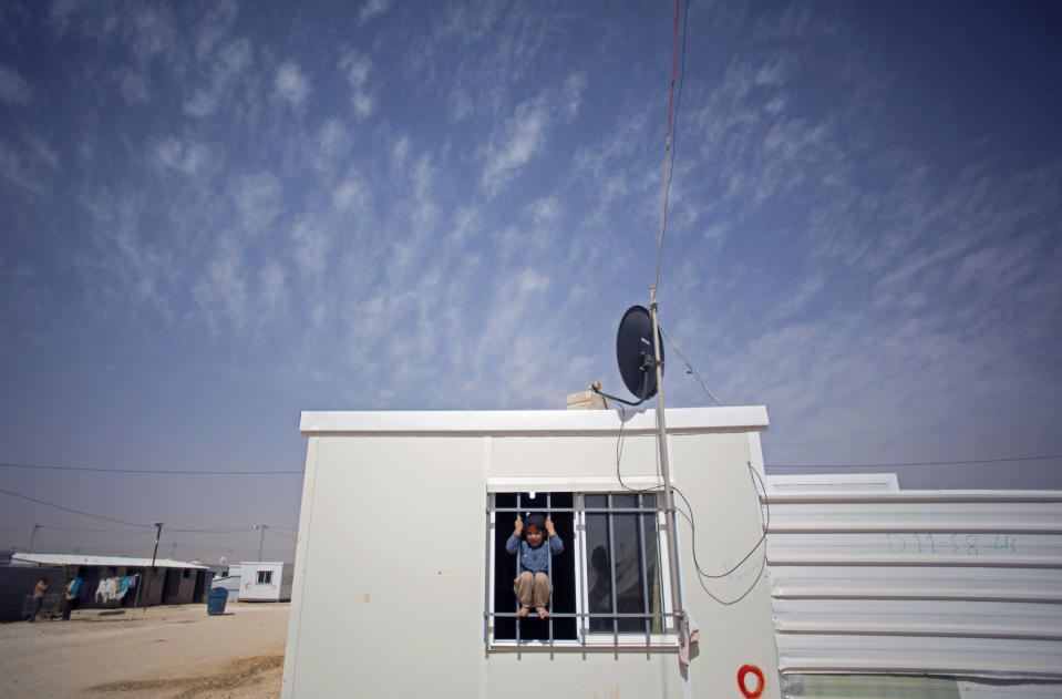 In this Thursday, April 17, 2014 photo, a Syrian boy plays on the window of a caravan at Zaatari refugee camp, near the Syrian border in Jordan. (AP Photo/Khalil Hamra)