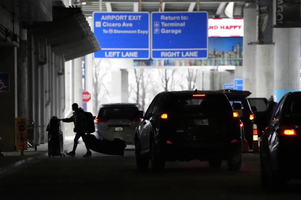 An airline passenger walks between ride share vehicles after arriving at Chicago's Midway Airport just days before a major winter storm Tuesday, Dec. 20, 2022, in Chicago. (AP Photo/Charles Rex Arbogast)