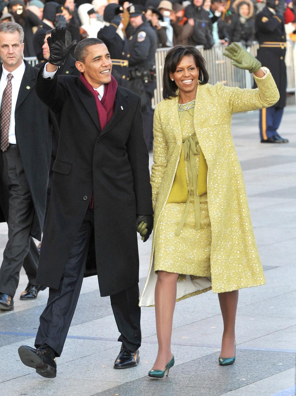 Barack and Michelle in a yellow-green coat, blouse, skirt, and gloves.