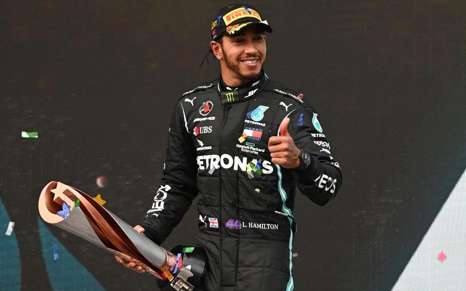 Mercedes' Lewis Hamilton celebrates on the podium with a trophy after winning the race and the world championship.  - REUTERS