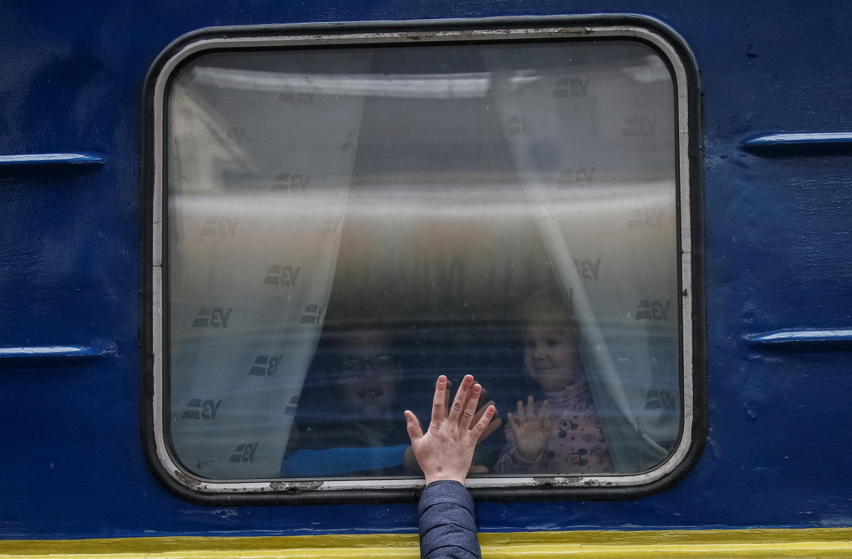 Children look out the window of a departing train in Kyiv on Thursday. 