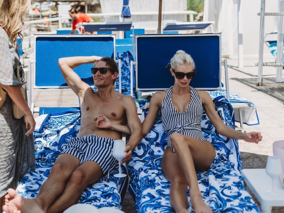 A man and woman sit on beach chairs.