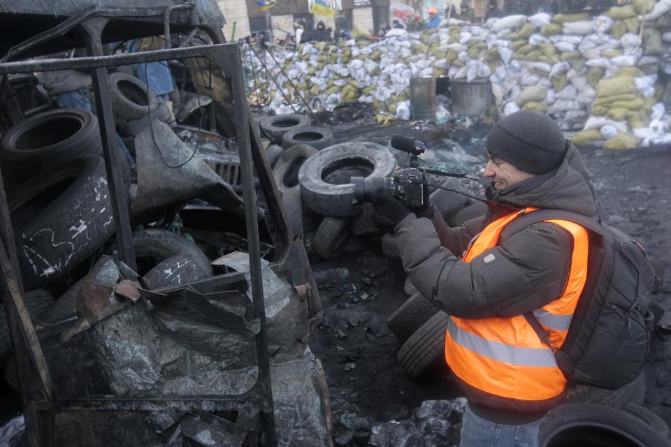 In this photo taken Monday, Jan. 27, 2014, journalist Ihor Medelyan, 32, makes photos as he talks to the Associated Press in an interview near barricades in central Kiev, the site of violent clashes between protesters and police. Medelyan quit the government-owned First National channel after the government violently dispersed a small peaceful protest rally and after his channel refused to objectively report on the event. (AP Photo/Sergei Chuzavkov)