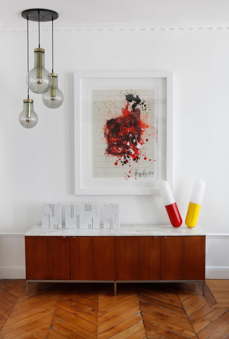 A vintage Florence Knoll rosewood cabinet with marble top from the 1960s on the original wood floors. On top of the cabinet are reversible marble vases by Angelo Margiarotti for Knoll and Pillola lamps for Cesare Casati and Emanuele Ponzi. The hanging lighting fixture is by RAAK and the artwork is by Philippe Pasqua.