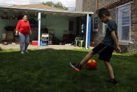 Eugenia Rodriguez, left, plays ball with her youngest son, Aaron, 6, in the backyard of her house Friday, July 2, 2021, in Chicago's Little Village neighborhood. Rodriguez hasn't been eligible for insurance coverage after overstaying a visitor visa from Mexico. She used to wake up every two or three hours at night to check on her mother. Since getting health insurance through the Illinois program, her mother has all the medications she needs. (AP Photo/Shafkat Anowar)