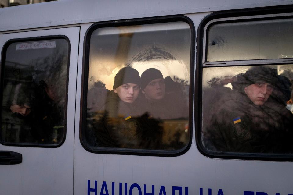 Members of National Guard of Ukraine look out of the window as they ride in a bus through the city of Kiev, Monday, Feb. 14, 2022. More NATO troops headed to Eastern Europe and some nations worked to move their citizens and diplomats out of Ukraine on Monday, as Germany's chancellor made a last-ditch attempt to head off a feared Russian invasion that some warn could be just days away.