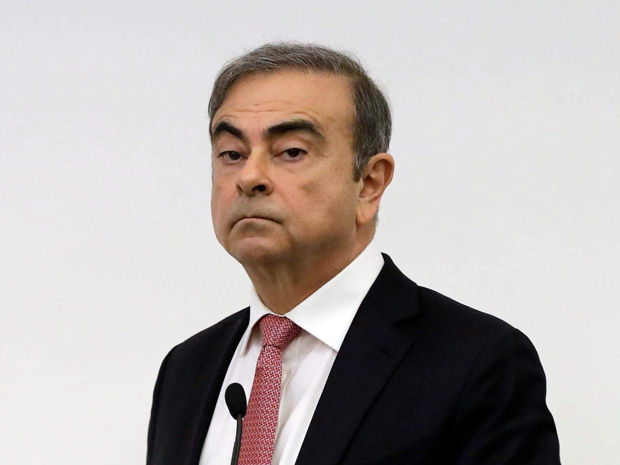 Former Nissan chairman Carlos Ghosn wears a black suit jacket, white shirt and pink tie.