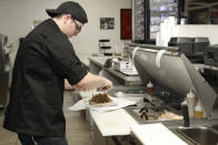 Chef Joseph Gattuso prepares a gyro sandwich in Schaumburg, Ill., on Sept. 6, 2019. He's working in the kitchen of Frato's Pizza, but filling an online order for the virtual restaurant Halal Kitchen. Frato's looks like a typical restaurant, but cooks there whip up dishes for four other restaurants at the same time. Thousands of restaurants are experimenting with virtual spin-offs, trying to capitalize on the rising popularity of online ordering. (AP Photo/Teresa Crawford)