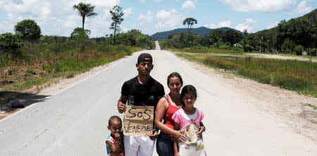 FILE PHOTO: Venezuelan family from Aragua state pose for a picture as they attempt to hitchhike toward Boa Vista city, after they obtained refugee status or temporary residence, through the Federal Police and the United Nations High Commissioner for Refugees (UNHCR), at the Pacaraima border control, Roraima state, Brazil August 10, 2018. REUTERS/Nacho Doce/File photo