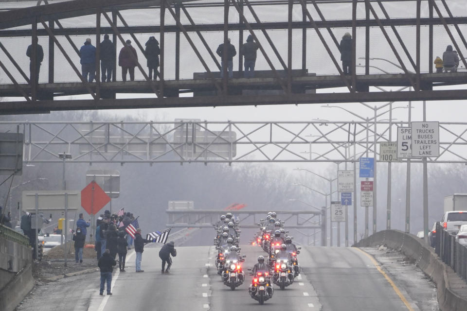 A procession carries the body of NYPD Officer Jason Rivera to a cemetery as people watch from an overpass in Yonkers, N.Y., Friday, Jan. 28, 2022. Rivera and his partner, Officer Wilbert Mora, were fatally wounded when a gunman ambushed them in an apartment as they responded to a family dispute last week. (AP Photo/Seth Wenig)