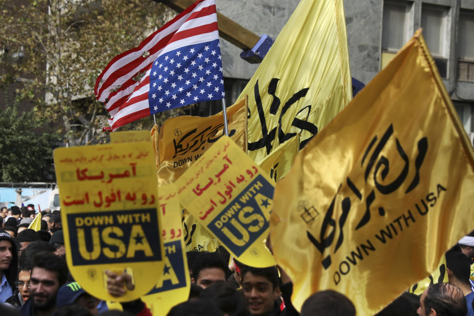 Demonstrators hold anti-U.S. banners and a torn makeshift U.S. flag upside down in an annual rally in front of the former U.S. Embassy in Tehran, Iran, Monday, Nov. 4, 2019. Reviving decades-old cries of "Death to America," Iran on Monday marked the 40th anniversary of the 1979 student takeover of the U.S. Embassy in Tehran and the 444-day hostage crisis that followed as tensions remain high over the country's collapsing nuclear deal with world powers. (AP Photo/Vahid Salemi)