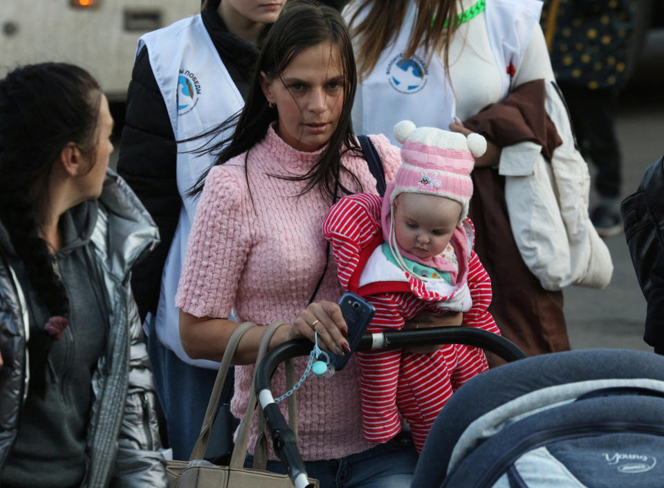 A woman carries a child as civilians evacuated from the Russian-controlled Kherson region of Ukraine arrive at a local railway station on November 2