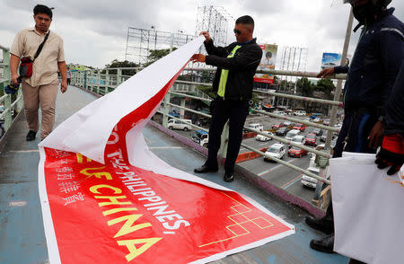 Traffic enforcers remove a banner reading "Welcome to the Philippines, Province of China" hanging on an overpass along the C5 road intersection in Taguig, Metro Manila, Philippines July 12, 2018. REUTERS/Erik De Castro