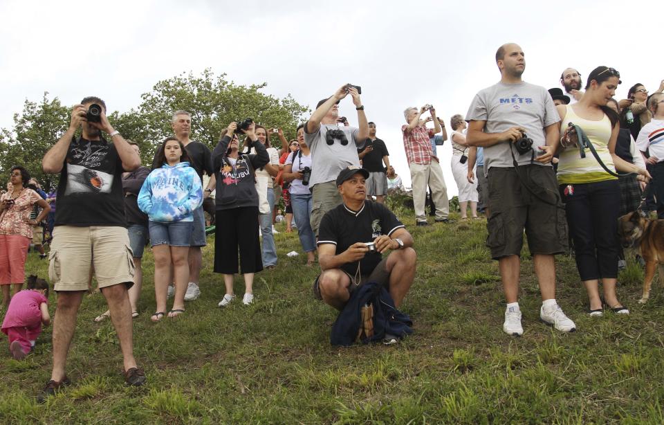 People gather to watch and take pictures as the space shuttle Enterprise is towed on a barge underneath the Verrazano-Narrows Bridge in New York, Sunday, June 3, 2012. The prototype space shuttle that arrived in New York City earlier this spring is headed to the Intrepid Sea, Air and Space Museum on the west side of Manhattan. (AP Photo/Seth Wenig)